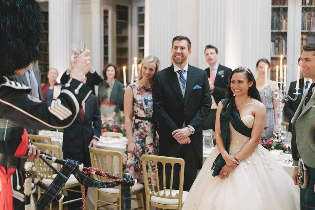 Bride and groom standing during the elegant dinner, guests congratulating — candlelit, white columns