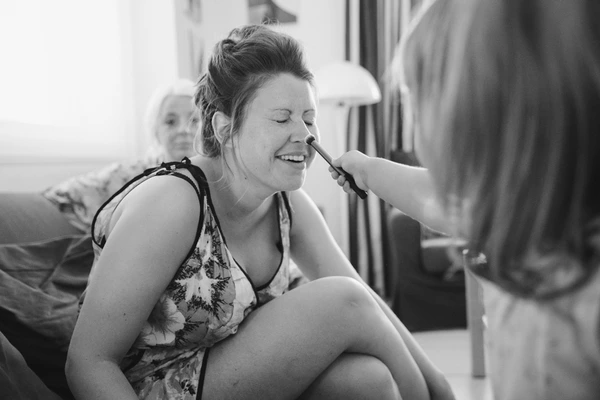 Bride smiling happily while getting ready — black-and-white intimate moment