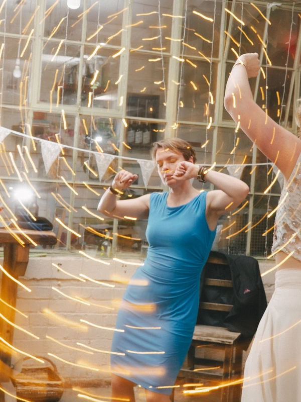 Woman in blue dress dancing with spiralling golden light beams around her — glass venue