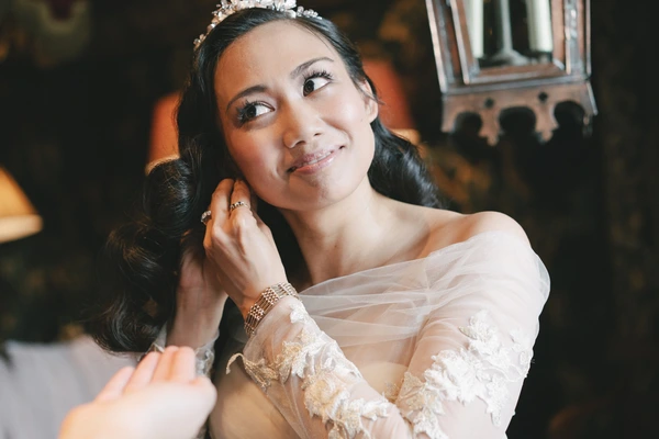 Bride with crystal hair jewel in white lace, pensive look, warm golden light at the venue