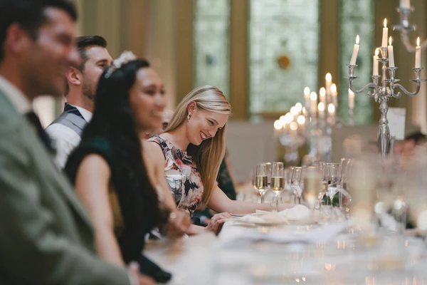 Guests at the wedding dinner — smiling blonde woman in floral dress, crystal candle holders