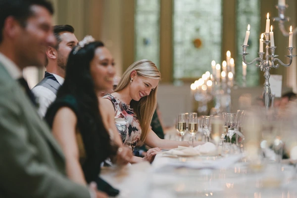 Guests at the wedding dinner — smiling blonde woman in floral dress, crystal candle holders