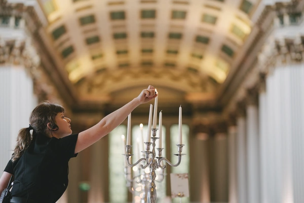 Woman lights candles on a silver candelabra under an elegant baroque terrace