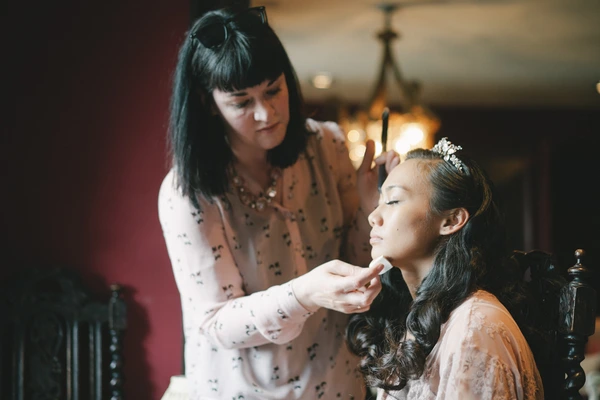 Makeup artist carefully works on the bride in a red salon before the wedding