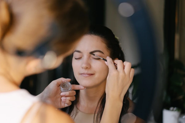 Close-up of a makeup artist detailing the bride's eyebrows. Natural wedding makeup session.