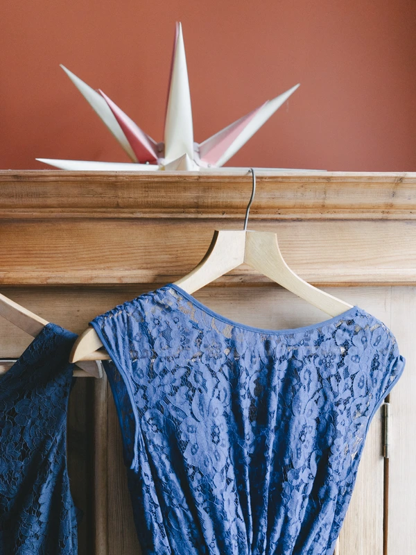 Blue lace dress on a white hanger in the dressing room beside a terracotta wall