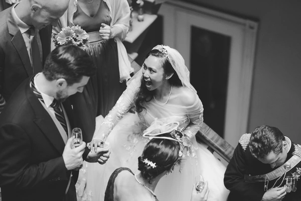 Bride with a laughing smile receiving congratulations from guests — lace, veil and pearls. Black-and-white.