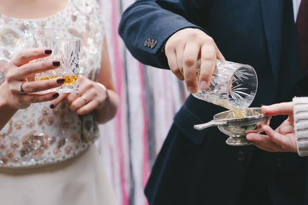 Groom pours whisky for the wedding toast — elegant gesture with crystal glass