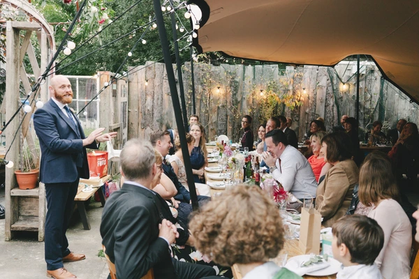 Groom gives a speech at the wedding dinner on a beautiful greenhouse terrace