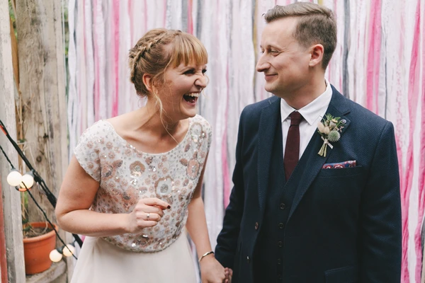 Bride and groom laughing at each other at the photo spot among colourful ribbons