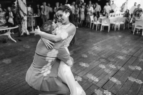 Black and white bride and groom first dance at wedding reception with guests watching.