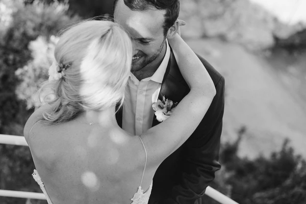 Bride and groom embrace in nature — black-and-white, forest backdrop, blonde bride with bouquet
