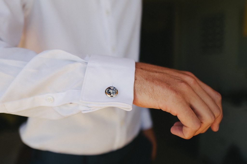 Groom's white shirt cuff detail — gold cufflink visible at the wrist, elegant wedding attire