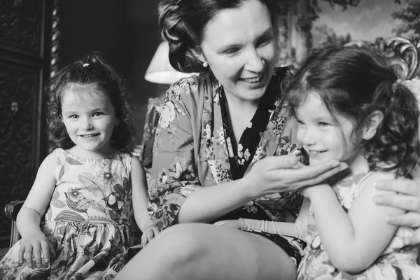 Mother and two daughters smiling at each other in warm, intimate black-and-white portrait