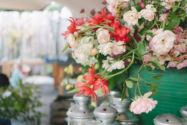 Wedding flowers — red gerberas, cream and pink peonies in metal vases, soft backlighting