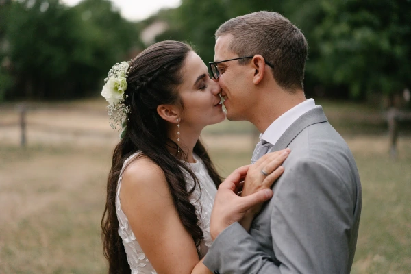 Couple kissing close-up at outdoor garden wedding with lace dress and tender expression.