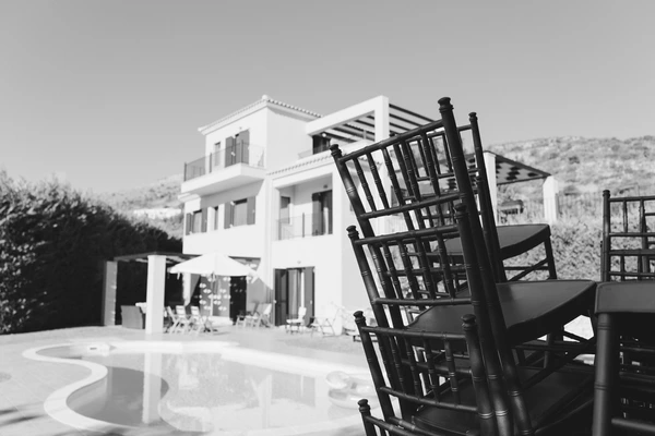 Black Chiavari chair on a pool terrace, white villa and Greek landscape in the background