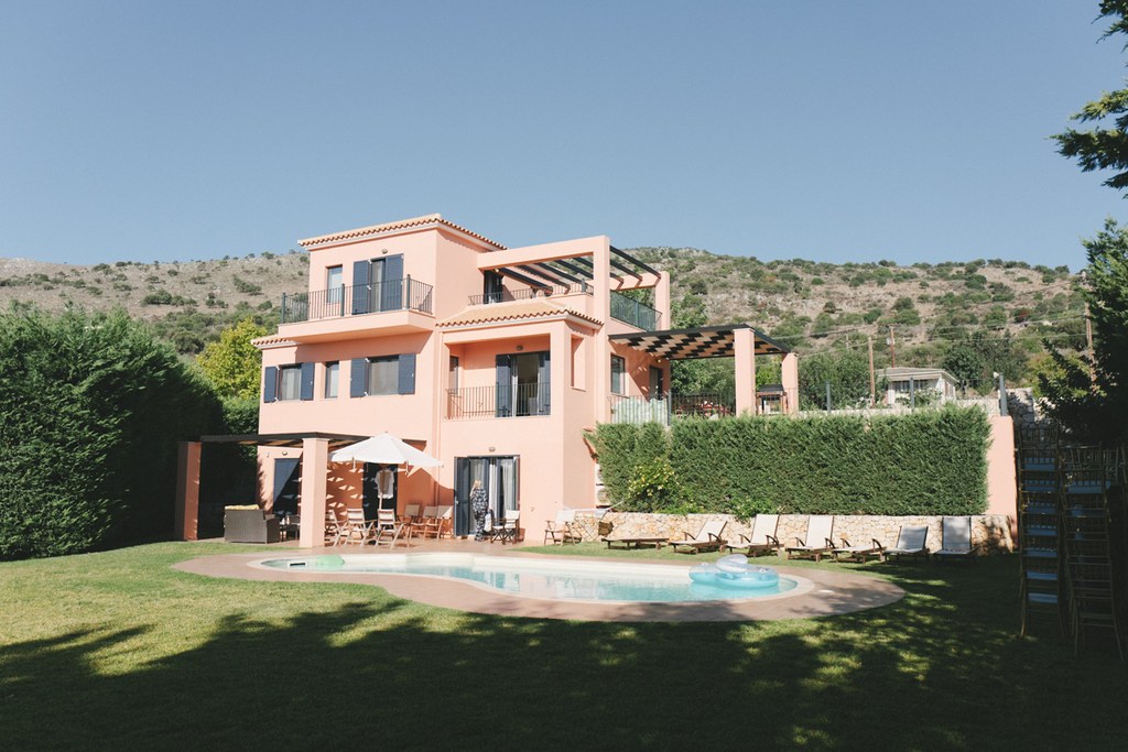 Terracotta Mediterranean villa with pool, sun loungers and a mountainous backdrop under clear sky