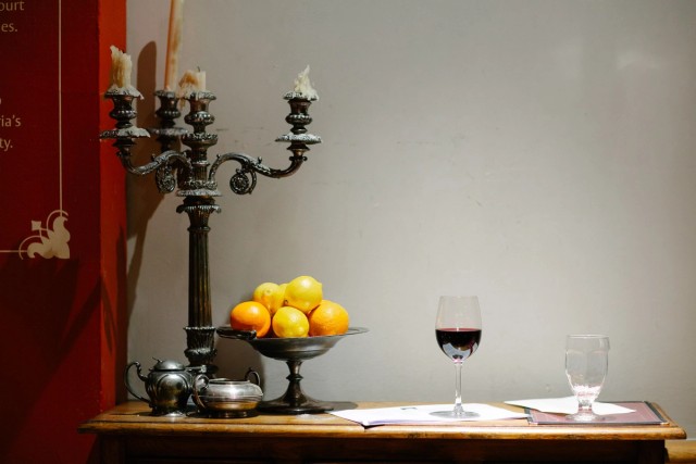 Table decoration in the Edinburgh Castle, candle holder and bowl of fruits with a glass of red wine on a table