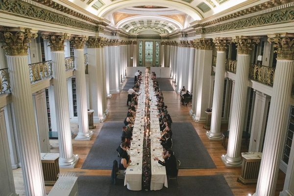 Wedding banquet hall from above — long table, golden colonnade, crystal chandelier, floral decoration