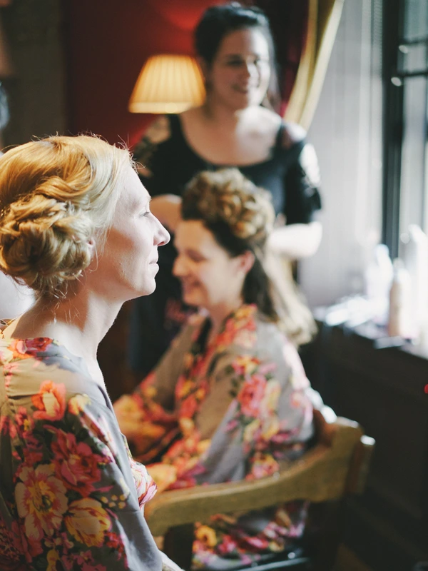 Bride in floral dress in profile — warm lamp light, interior scene before the ceremony