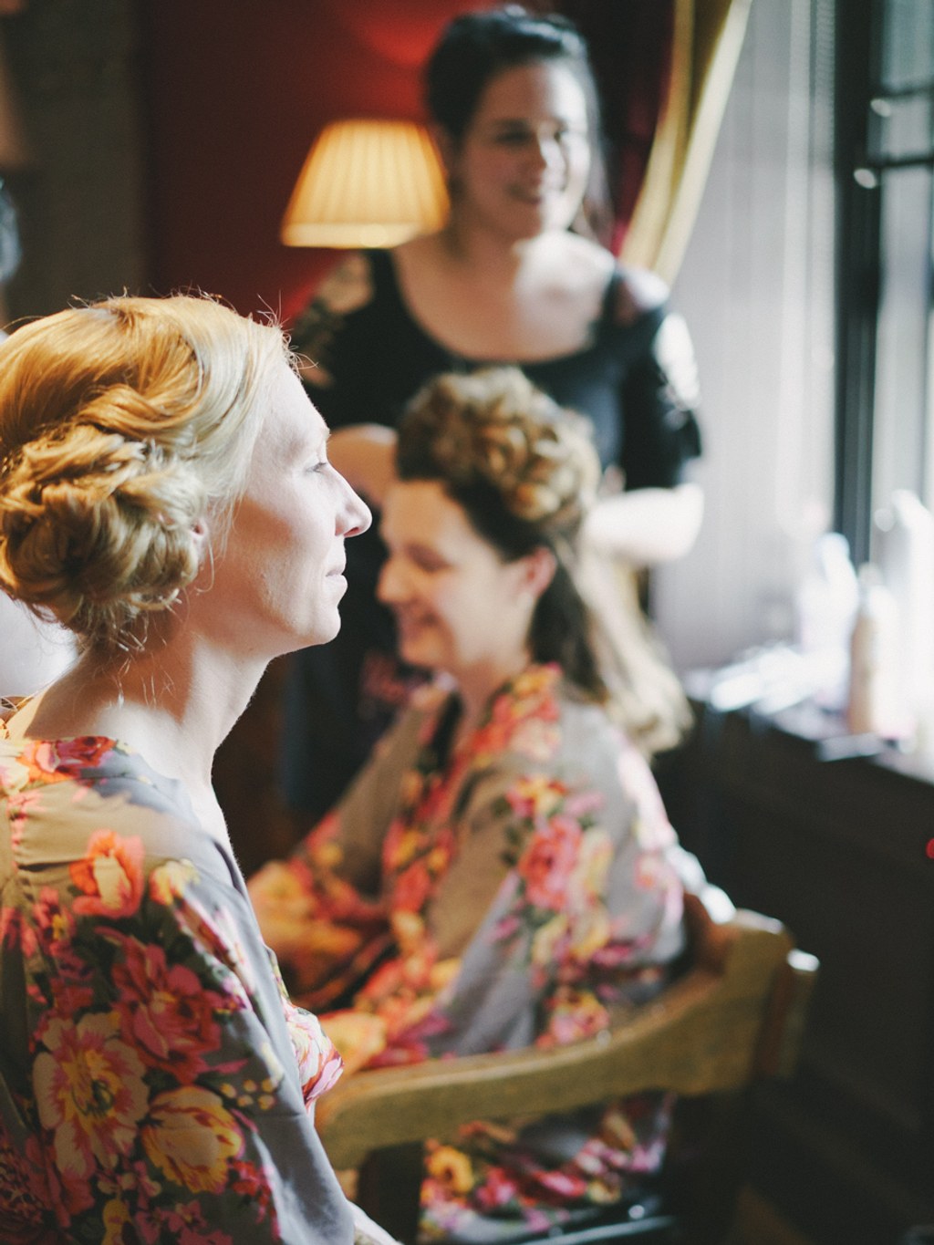 Bride in floral dress in profile — warm lamp light, interior scene before the ceremony