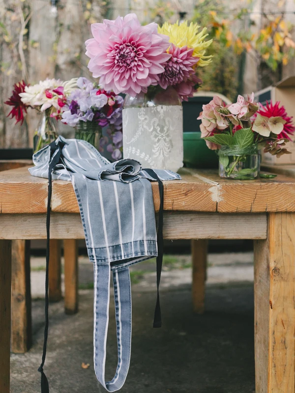 Wedding bouquet on a wooden table with rustic stone wall — pink dahlias and burgundy blooms