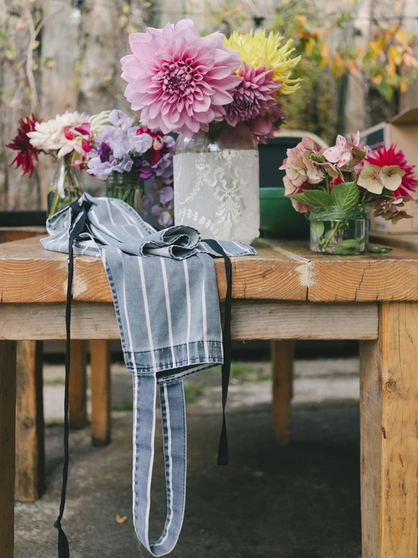 Wedding bouquet on a wooden table with rustic stone wall — pink dahlias and burgundy blooms