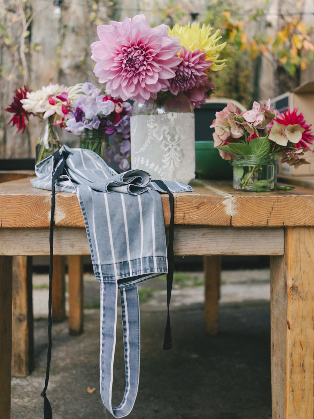 Wedding bouquet on a wooden table with rustic stone wall — pink dahlias and burgundy blooms