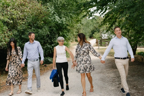 Group of wedding guests walking and laughing together on a forest path. Candid guest photography.