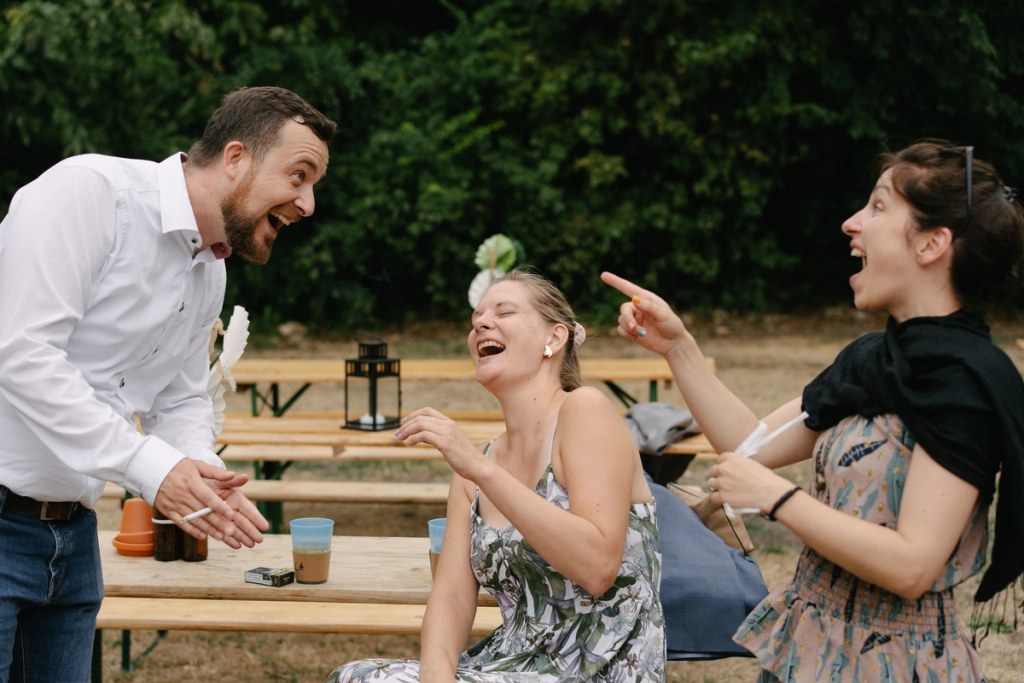 Wedding guests chatting and laughing at an outdoor reception.