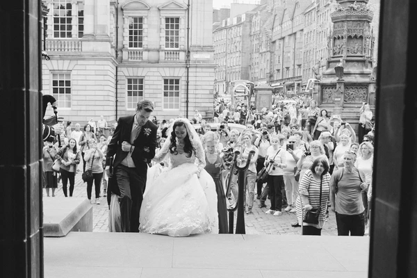 Bride and groom cross the square to greet a welcoming crowd — baroque buildings around