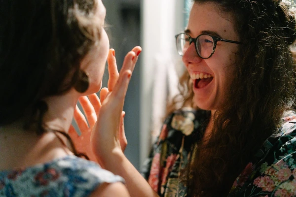 Close-up of a woman laughing joyfully while helping the bride with her makeup. Genuine wedding emotions.