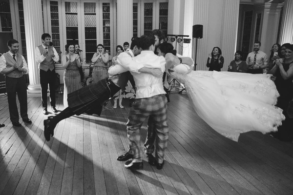 Bride and groom dance in the elegant hall, her long gown swinging — guests applauding and smiling