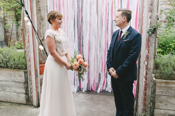 Bride and groom look at each other smiling before the ceremony at a vintage industrial venue