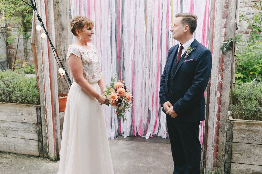 Bride and groom look at each other smiling before the ceremony at a vintage industrial venue