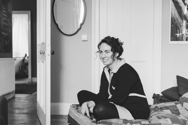 Bride smiling while getting ready in the hotel room, bright natural light