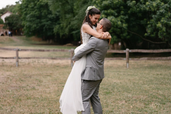 Bride and groom embracing tenderly during outdoor wedding reception with natural garden background.