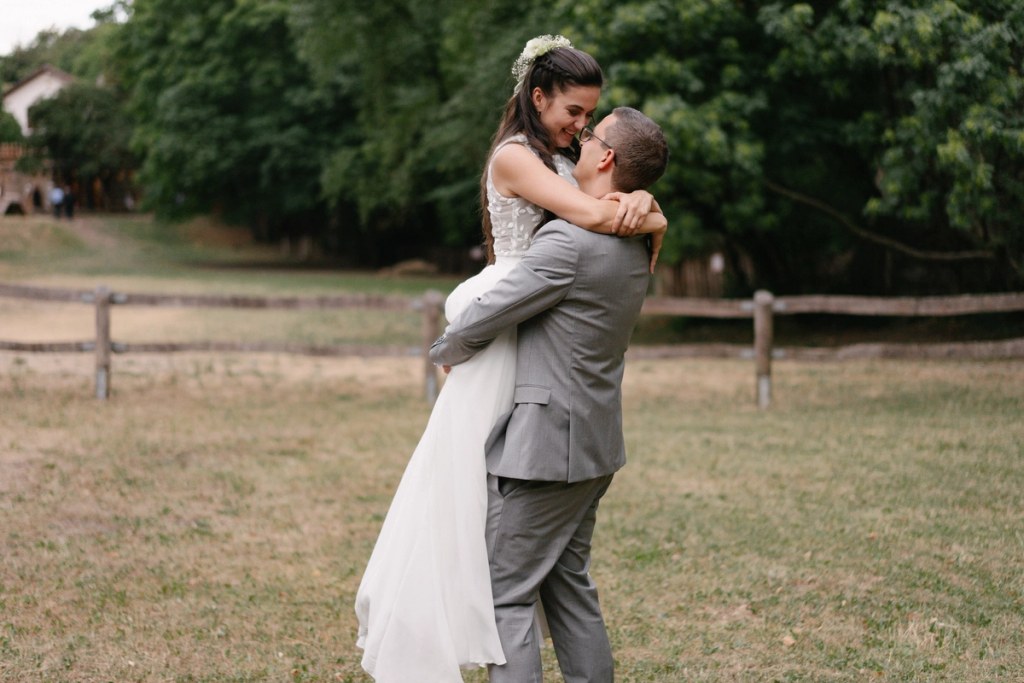 Bride and groom embracing tenderly during outdoor wedding reception with natural garden background.