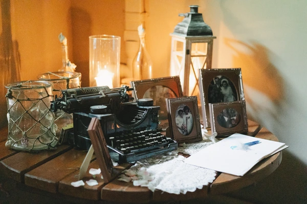 Vintage wedding table decor — old typewriter, sepia family photos, candles and warm golden light