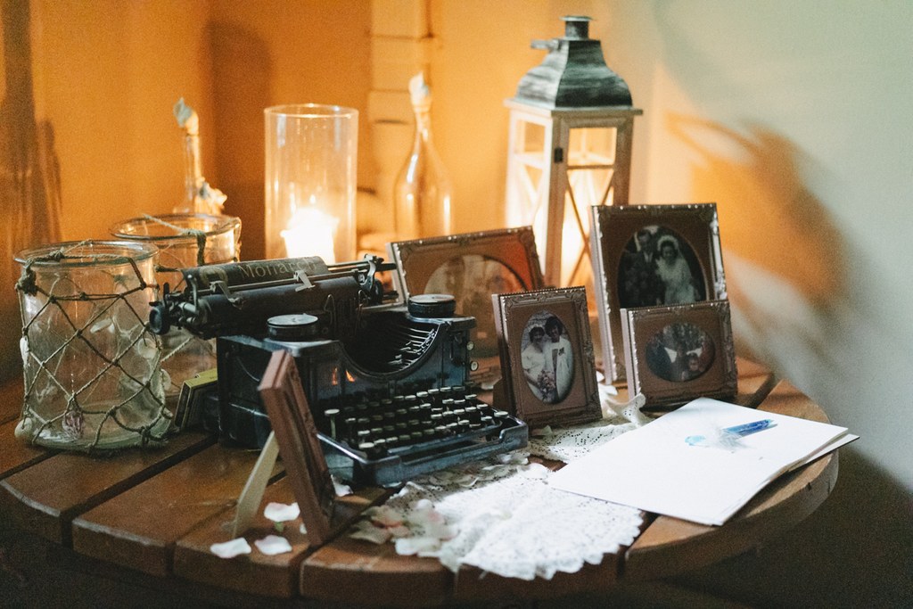 Vintage wedding table decor — old typewriter, sepia family photos, candles and warm golden light