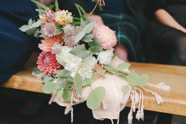 Bridal bouquet with pink and white peonies, eucalyptus and natural ribbon on a wooden surface
