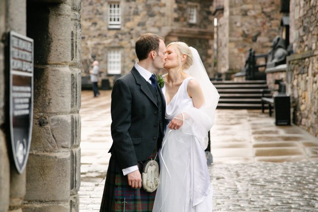 Bride and groom kissing in the Edinburgh Castle inner court with the backdrop of historic castle walls