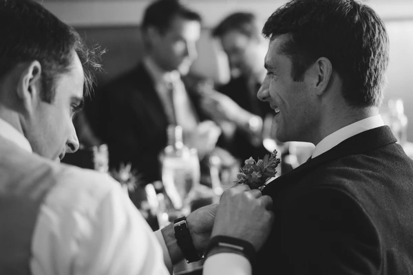 Groom smiling and talking with a man at the wedding reception — black-and-white