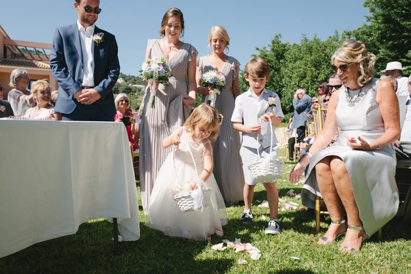 Little girl scatters flower petals during the ceremony among the guests — joyful summer moment