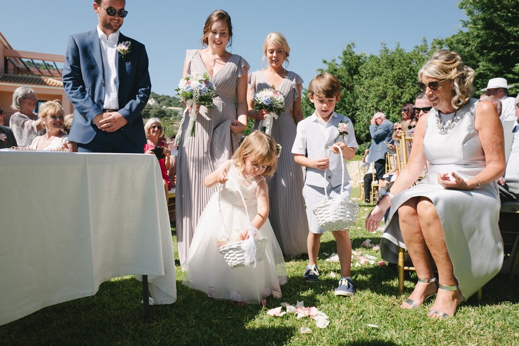 Little girl scatters flower petals during the ceremony among the guests — joyful summer moment