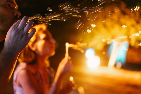 Wedding guest catching sparkler light at evening party — golden sparkle effects, candid moment, festive outdoor celebration.