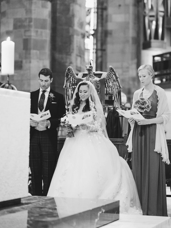 Bride in white dress and veil stands at the altar with groom and witnesses — black-and-white