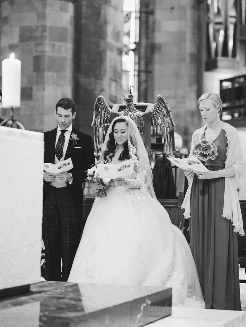 Bride in white dress and veil stands at the altar with groom and witnesses — black-and-white