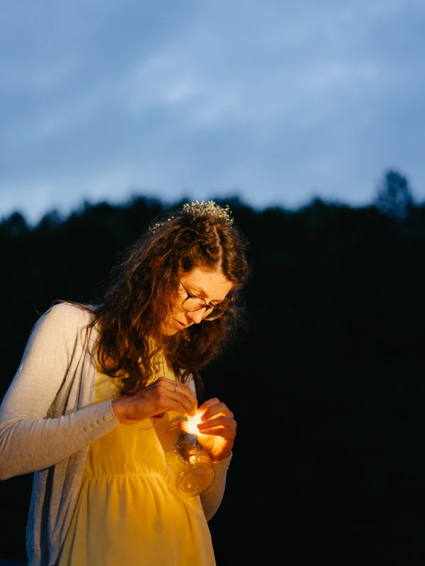Bride holding lantern candle at twilight wedding with white dress and golden light glow.